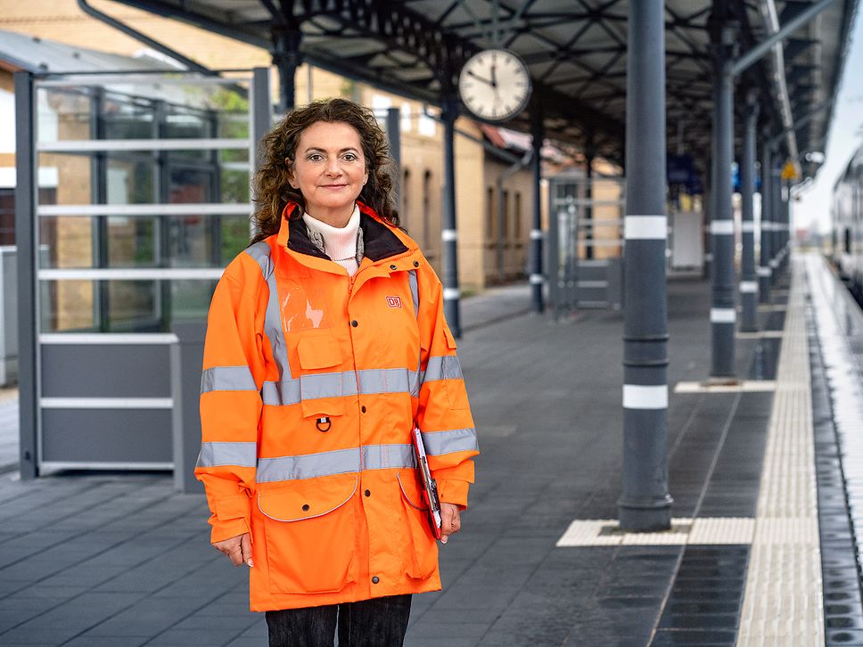 Eine Projektingenieurin steht in Warnkleidung am Bahnsteig eines Bahnhofs