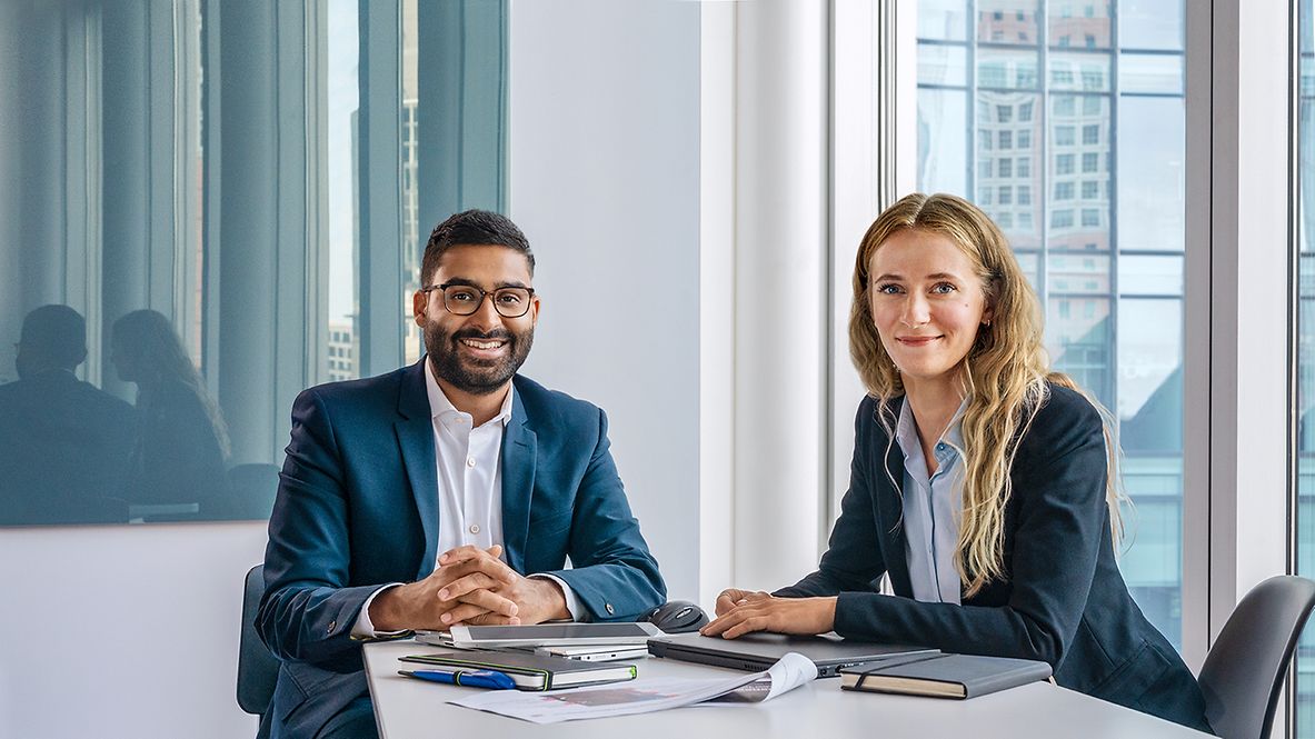 Zwei Berater sitzen in einem Besprechungsraum und ihre Unterlagen liegen auf dem Tisch